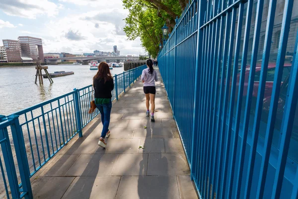 People strolling and jogging along the river Thames in London, UK