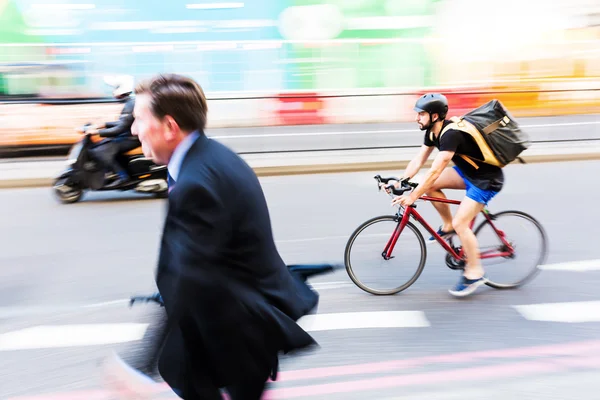 Cyclist and businessman in motion blur in the city traffic of London, UK