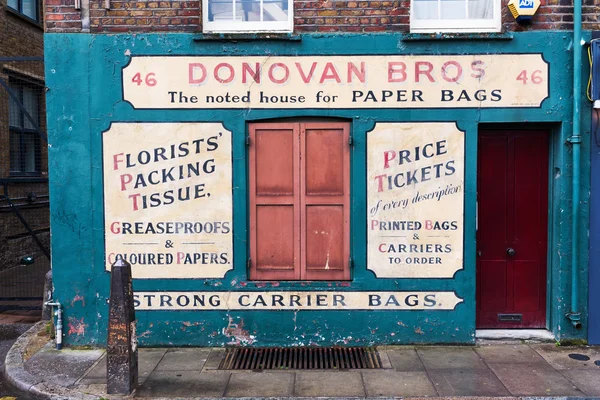 Old building with antique signage of a paper bag merchant in Shoreditch, London, UK