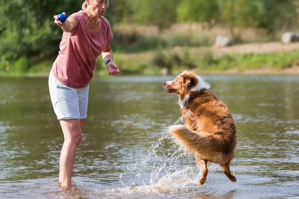 Woman plays with a dog in a river