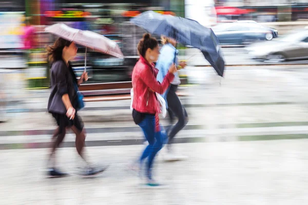 People in motion blur walking in the rainy city