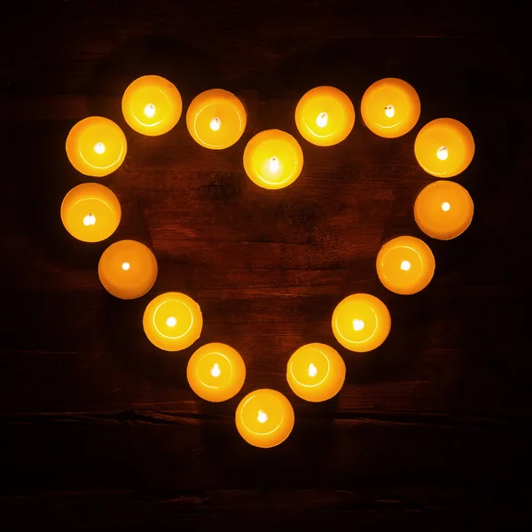 Burning tea lights shaped like a heart in the dark