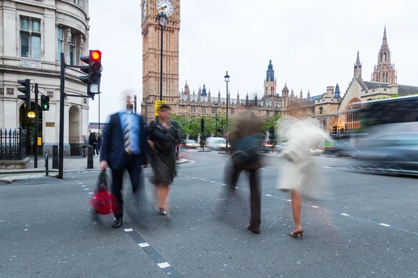 People in motion blur crossing a street near Westminster Palace in London, UK