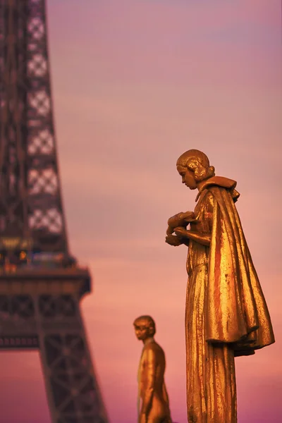 Golden sculptures on the Trocadero square in Paris, France, with the Eiffel Tower in the background in dawn light