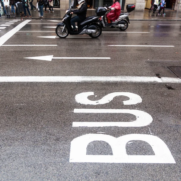 Bus lane of a city street with scooterists in the background