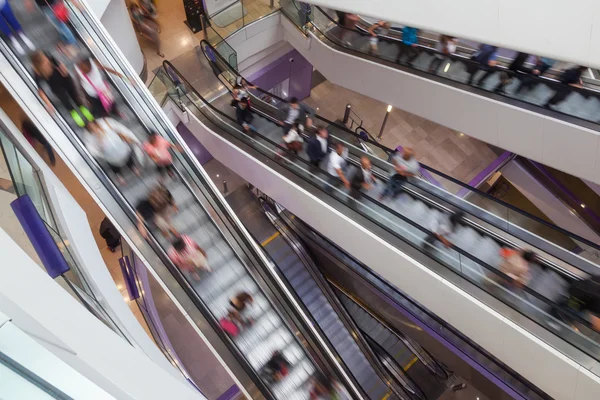 Escalators in a shopping mall with people in motion blur