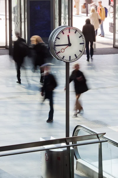 Clock in a station with people in motion blur