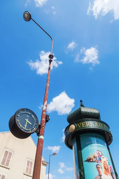 Antique advertising column and a lamp post with clock in Versailles, France