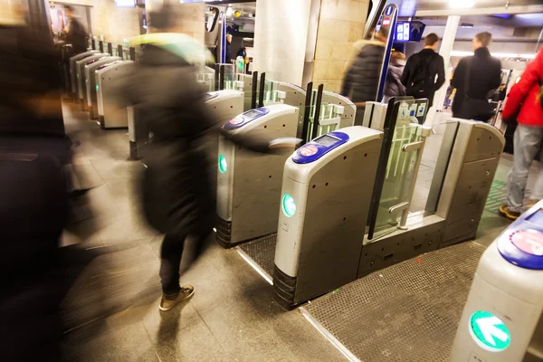 People in motion blur at a turnstile of a metro station