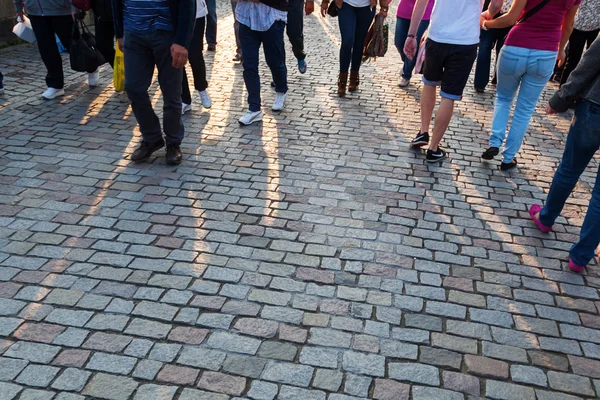 People crowd in backlit walking on cobblestone road