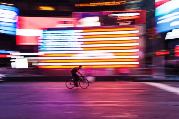 Bicycle rider in front of US flag at Times Square, NYC