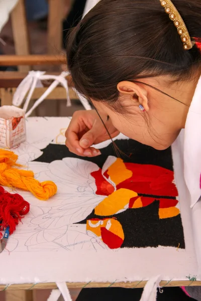Vietnamese artist embroiders a floral art piece.
