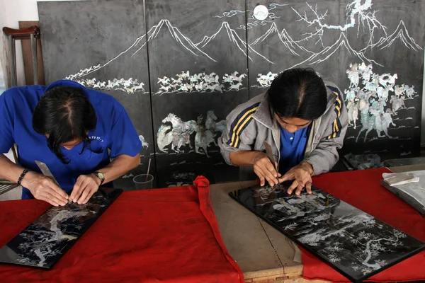 Unidentified artists works on acrylic and lacquer art pieces.