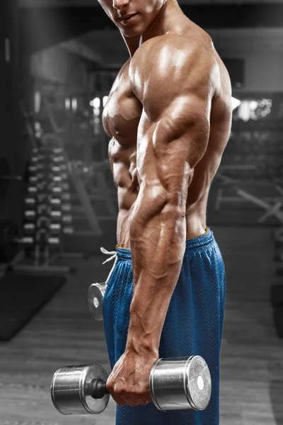 Muscular man posing in gym, showing triceps. Strong male naked torso abs, working out, focus on the hand