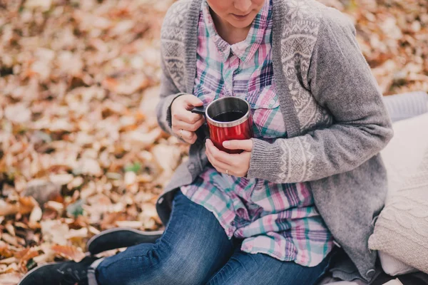 Young woman reading book and drinking tea in a forest