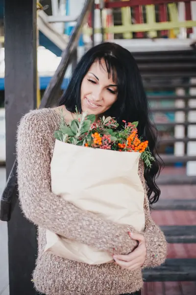 Young woman holding paper bag with ingredients for xmas wreath