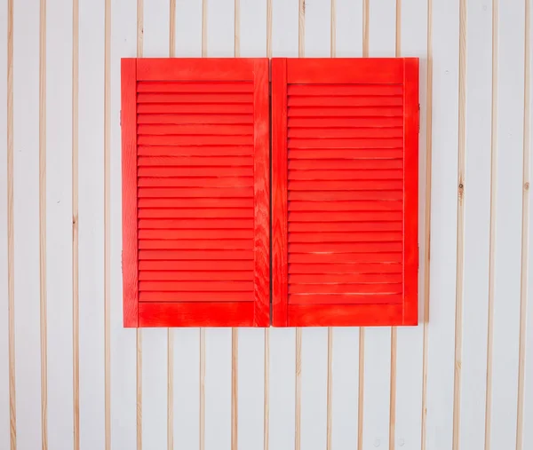 Red wooden shutters on a white wall