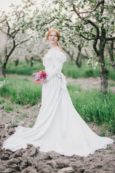 Beautiful bride in a vintage wedding dress posing in a garden