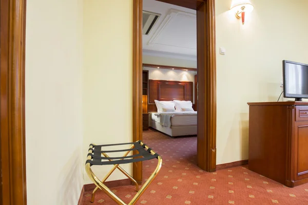 Interior of a hotel suite, bedroom visible through doorway