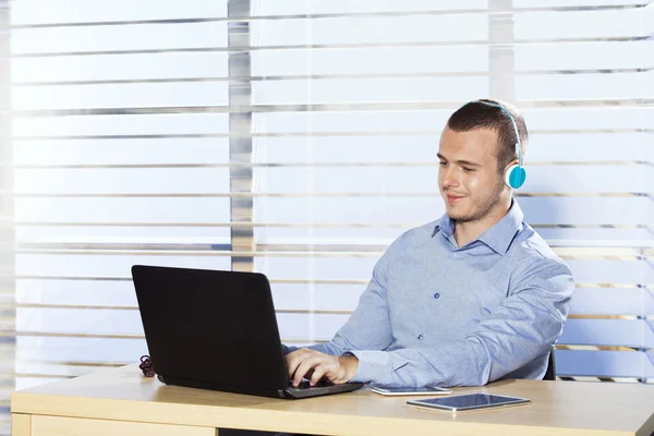 Young man working on computer and listening to music