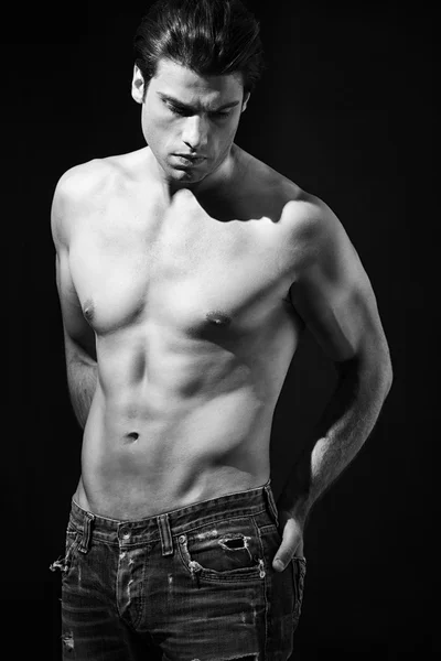 Shirtless muscular man in jeans in black and white