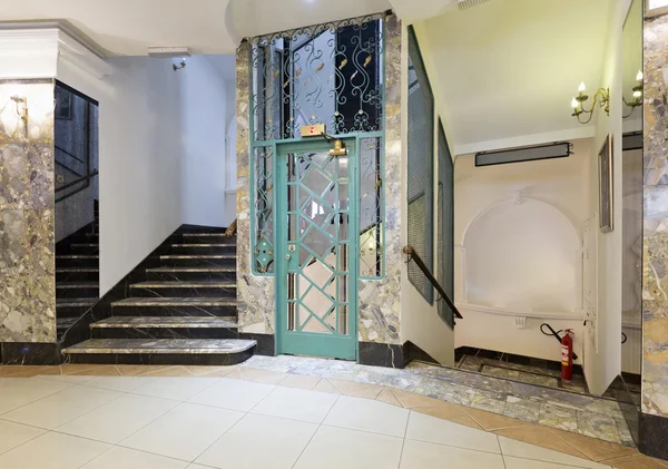 Interior of a corridor with passenger lift and marble stairs