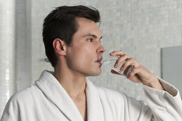 Man in bathrobe having a glass of water