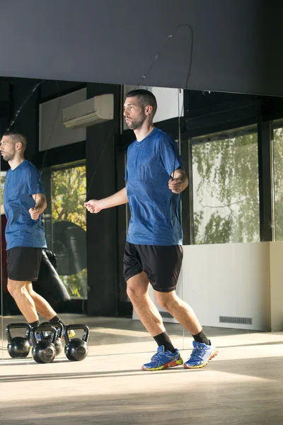 Young man exercising with jump-rope at the gym