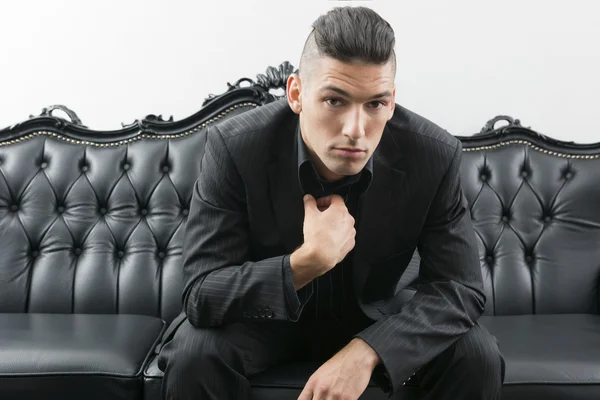 Young man in business suit sitting on leather sofa