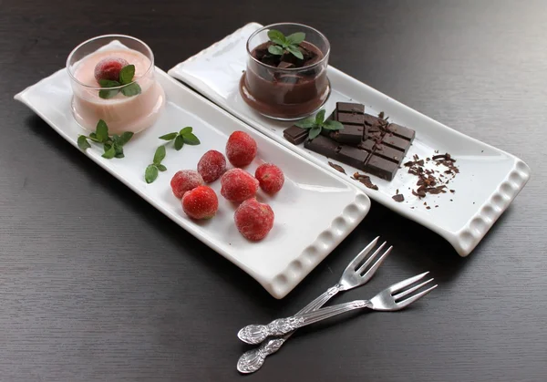 Pudding with chocolate crumbs and strawberry pudding with frozen strawberries and mint in a glass cream bowls