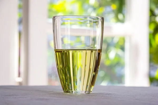 Glass With Olive Oil Placed On A Table Against The Window.