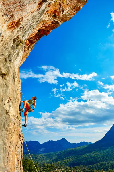 Rock climber climbing up a cliff