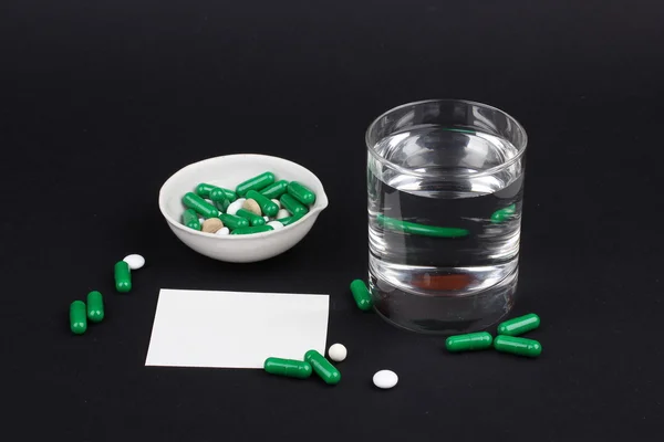 Pills with glass of water to drink the pills on dark black background. Pain