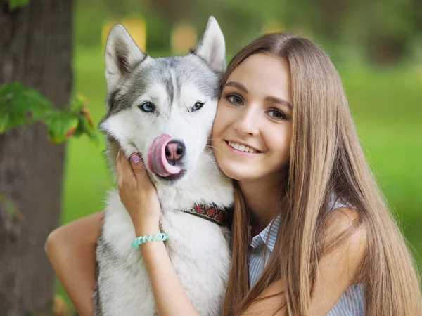 Attractive young woman hugs funny siberian husky dog who show its tongue