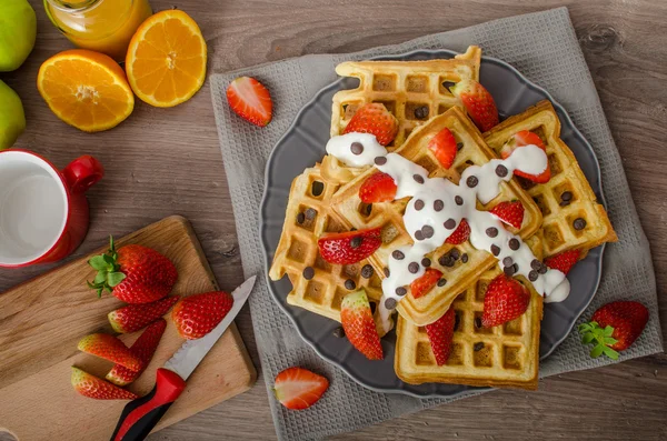 Homemade waffles with maple syrup and strawberries