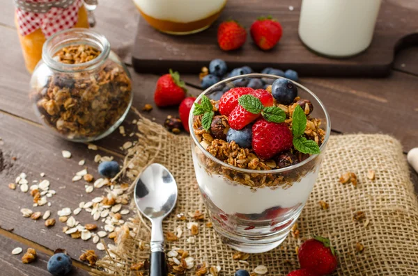 Yogurt with baked granola and berries in small glass