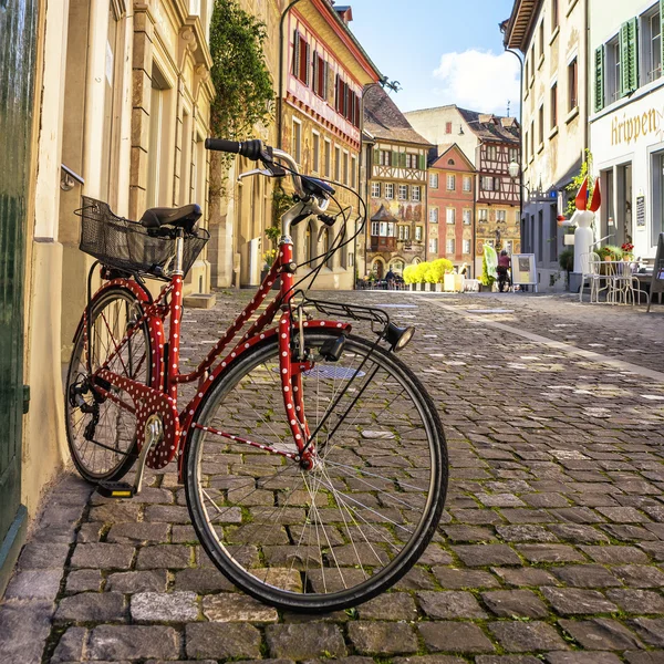 Red bicycle parked in street with ancient europe city in backgro