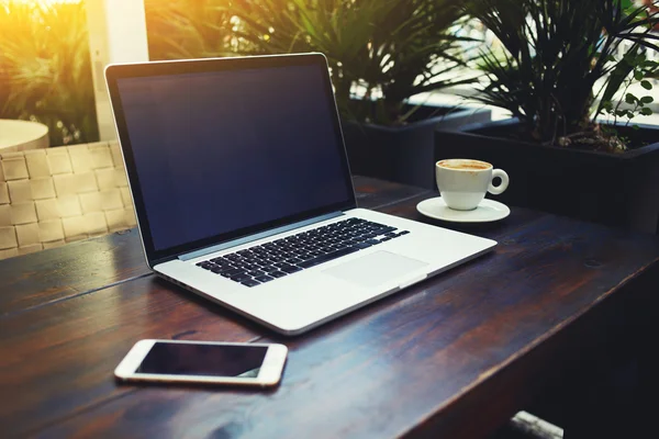 Laptop computer near mobile phone and cup of tea