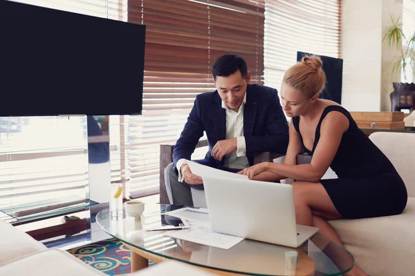 Young man and woman skilled CEOs  while are sitting in informal atmosphere near screen with copy space