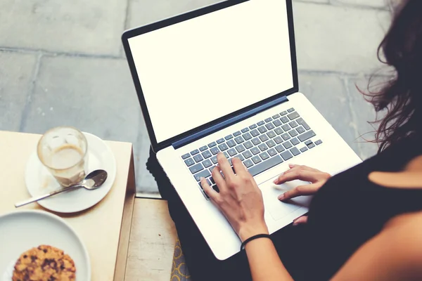 Back view of business woman is typing text on laptop keyboard during work break in cafe.