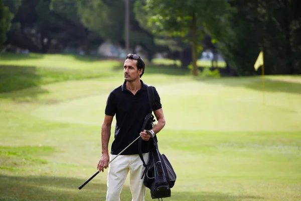 Golf player carrying his bag and walking on golf course