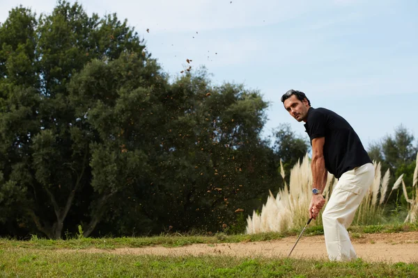 Strong golf shot of handsome player standing on golf course