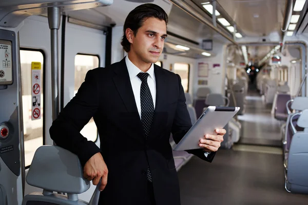 Businessman working with digital tablet on the way to work in train