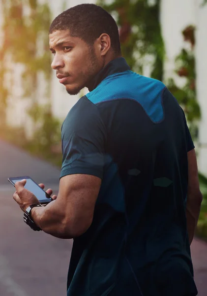 Attractive dark skinned runner walking on the road resting after fitness training outdoors