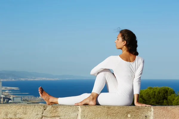Yoga on high altitude with big city and sea on background,young woman seated in yoga pose on amazing city background,woman meditating yoga and enjoying sunny evening, woman makes yoga on mountain hill