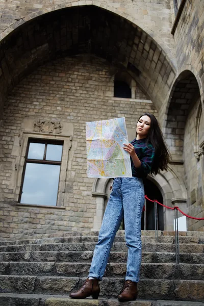 Beautiful tourist woman on vacation with a map in antique gothic city,young traveler girl searching right direction on city map, pretty young female tourist studying a map standing in gothic quarter