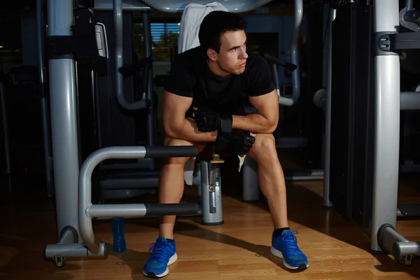 Young athlete seated on gym equipment