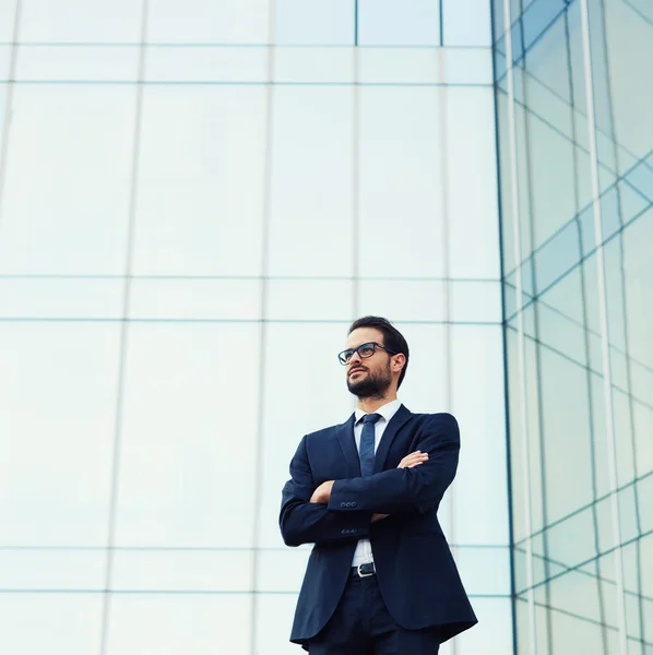 Business man in glasses standing near skyscraper