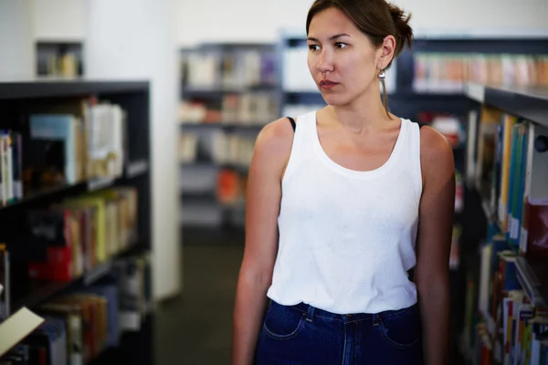 Asian female standing near bookshelves