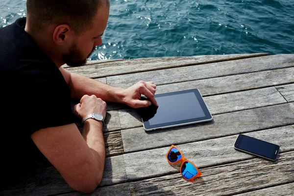 Man using digital tablet near sea